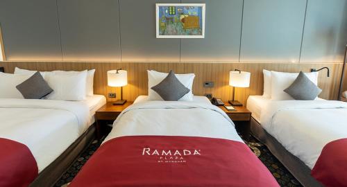 a hotel room with two beds and two lamps at Ramada Plaza by Wyndham Dolsan Yeosu in Yeosu