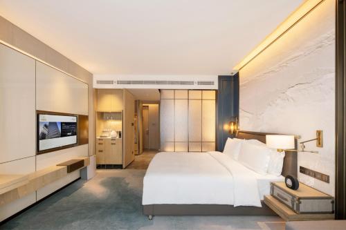 a bedroom with a large white bed and a television at 青岛海天大酒店 山海相拥典雅奢华 in Qingdao