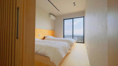 two beds in a room with a large window at Private Villa 蒼 Lala & Lino in Kyotango