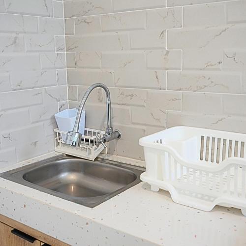 un fregadero en una cocina con una pared de ladrillo blanco en D'kraton Villa by Dparagon, en Timuran