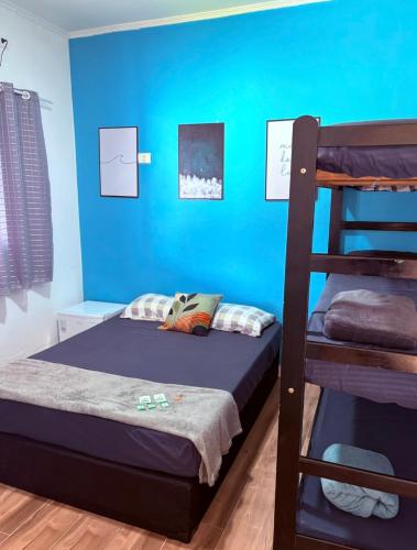 a bedroom with a blue wall and a bunk bed at Pousada Lemon Suítes - Praia do Sesc Acesso Vista Linda e Centro in Bertioga
