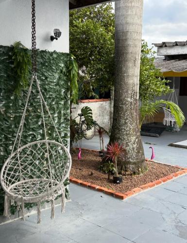 a swinging chair in front of a tree at Pousada Lemon Suítes - Praia do Sesc Acesso Vista Linda e Centro in Bertioga