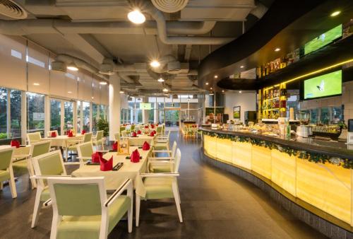 a restaurant with white tables and chairs and a bar at Montgomerie Links Hotel & Villas in Hoi An