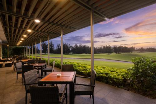 a patio with tables and chairs and a view of a golf course at Montgomerie Links Hotel & Villas in Hoi An