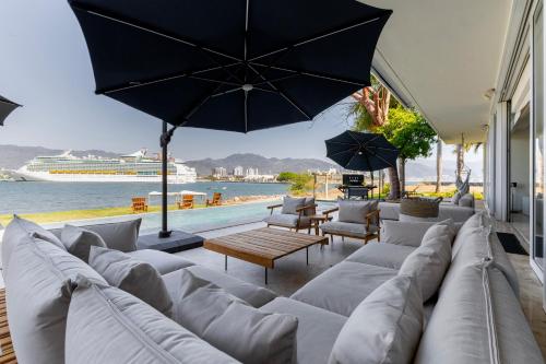 sala de estar con sofás blancos y sombrilla en Capitalia Tres Mares Beach Residences & Marina, en Puerto Vallarta
