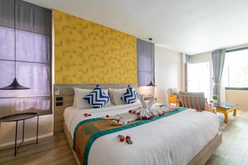 a bedroom with a large bed with a yellow wall at Antiya Hotel Phuket in Phuket Town