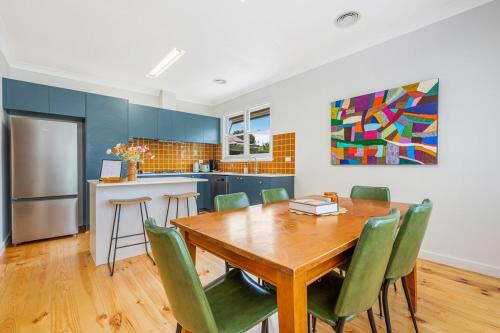 a kitchen with a wooden table and green chairs at Tara House, Bendigo in Bendigo