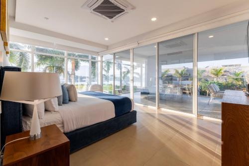 a bedroom with a bed and large glass windows at Capitalia Tres Mares Beach Residences & Marina in Puerto Vallarta
