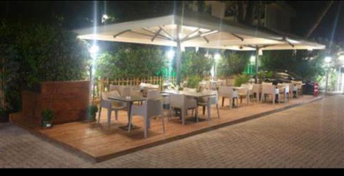 a restaurant with white tables and chairs at night at Hotel Carlton in Riccione