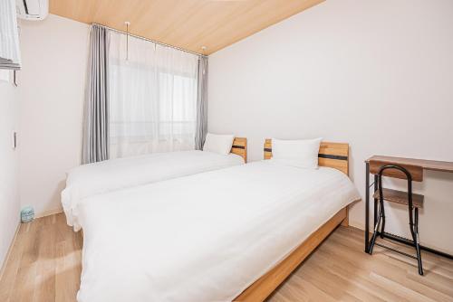 two beds in a room with a window at タスキスマート池袋一号館Tasuki Smart Ikebukuro1 in Tokyo