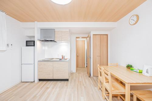 a kitchen with a white refrigerator and a wooden table at タスキスマート池袋一号館Tasuki Smart Ikebukuro1 in Tokyo