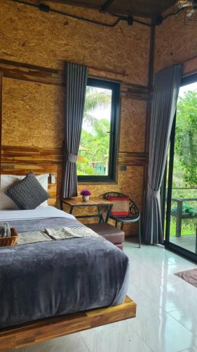 a bedroom with a bed and a large window at Baan Suan Hill Resort in Ban Tha Khun