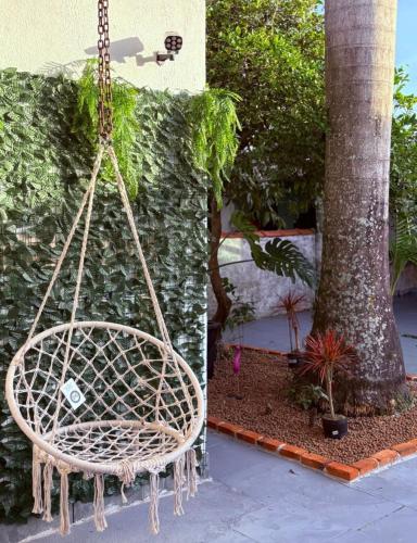 a rattan swing hanging from a tree at Pousada Lemon Suítes - Praia do Sesc Acesso Vista Linda e Centro in Bertioga