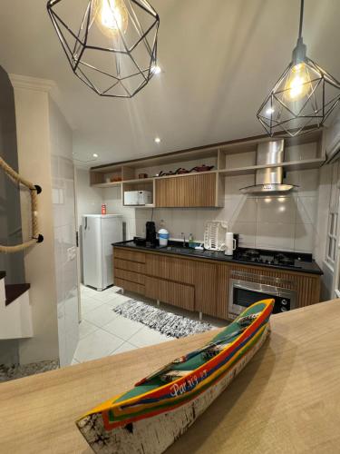 a kitchen with a table with a surfboard on the counter at Casa em condomínio fechado Paraty - KG Home in Paraty