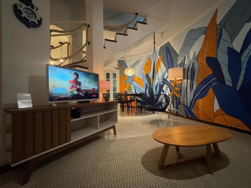 a living room with a flat screen tv and a mural at Casa em condomínio fechado Paraty - KG Home in Paraty
