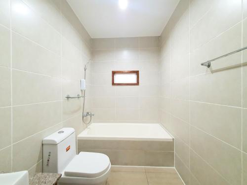 a white bathroom with a tub and a toilet at Koregon Pool Villas in Fort Stotsenburg