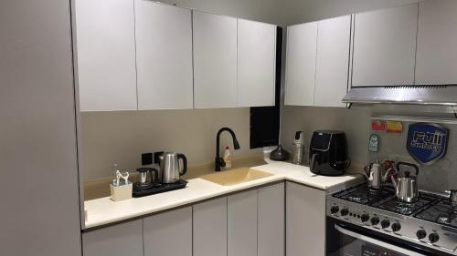 a small kitchen with white cabinets and a stove at شقة أنيقة بغرفتين نوم وصالة in Al Khobar