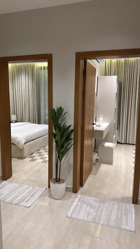 a bedroom with a bed and a potted plant at شقة أنيقة بغرفتين نوم وصالة in Al Khobar