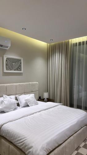 a bedroom with a large bed with white sheets at شقة أنيقة بغرفتين نوم وصالة in Al Khobar