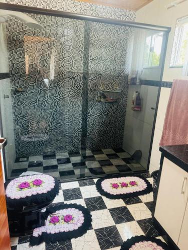a bathroom with a shower with flowers on the floor at Casa de Campo Recanto Paraíso na Rota das Cachoeiras in Prudentópolis