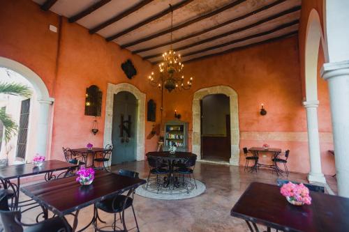 a dining room with tables and chairs and a chandelier at Hacienda Sacnicte in Izamal