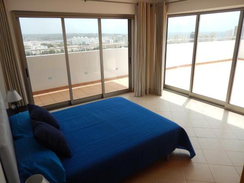 a bedroom with a blue bed and large windows at Atlantico Apartments in Portimão