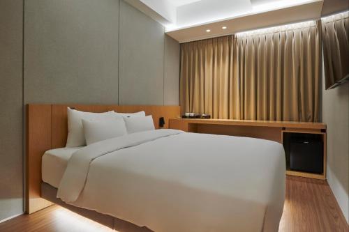 a bedroom with a large white bed and a window at 88Hotel in Seoul