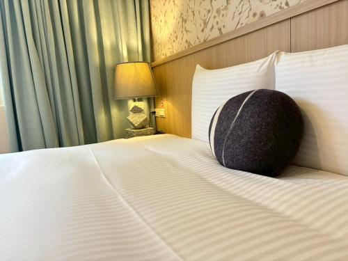 a bed with a pillow sitting on top of it at Tc慢旅花蓮館-近東大門夜市市中心 in Hualien City
