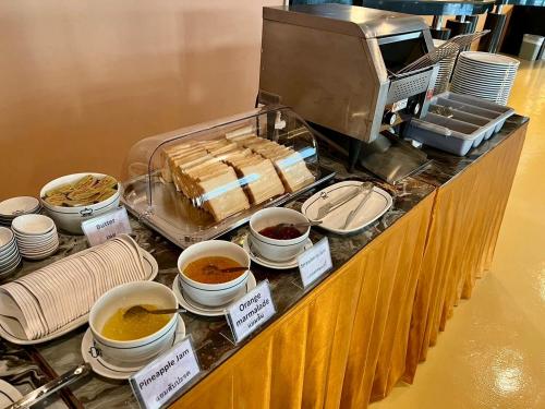 een buffet met kommen eten en kopjes koffie bij Crown Pattaya Beach Hotel in Pattaya