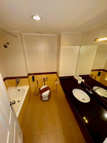 a bathroom with a tub and a toilet and a sink at Crown Pattaya Beach Hotel in Pattaya