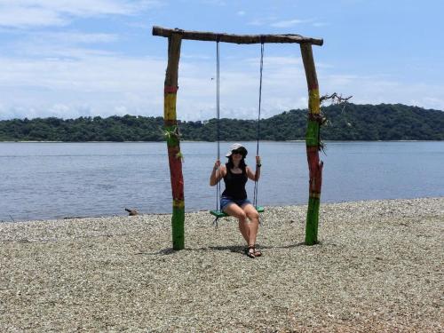 a woman sitting on a swing on the beach at Casa Mares in Lepanto