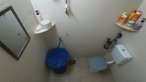 a bathroom with a toilet and a blue bucket at HOMESTAY Rezeki in Batu Gajah
