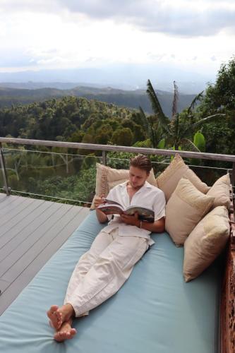 a man laying on a bed reading a book at Harvest Palace Munduk in Munduk
