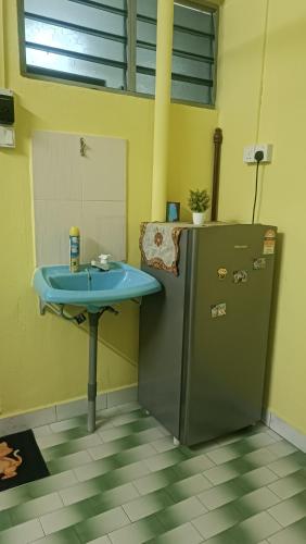 a bathroom with a sink next to a refrigerator at HOMESTAY Rezeki in Batu Gajah