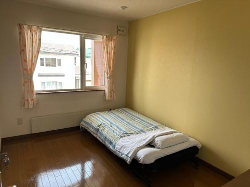 a bed in a room with a window at 民泊 SUMiKA in Kushiro