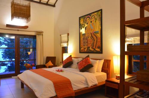 a bedroom with a large bed with a painting on the wall at Cocotinos Sekotong Lombok in Sekotong