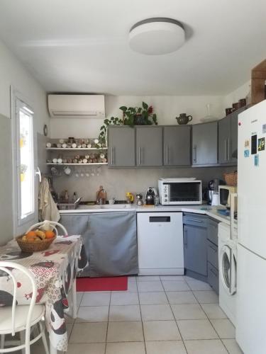 une cuisine avec une table et un réfrigérateur blanc dans l'établissement rez de chaussée de villa, à La Colle-sur-Loup