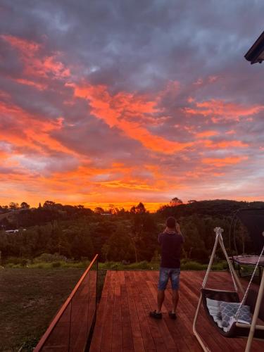 a man standing on a deck watching the sunset at Sunrise to Sunset Coastal Escape B&B in Auckland
