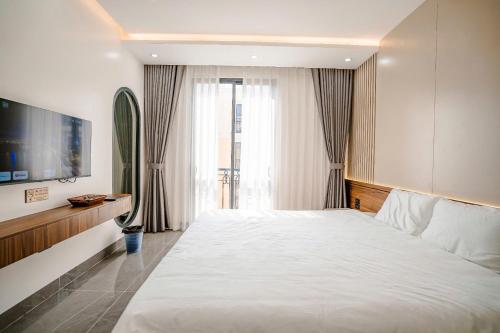 a bedroom with a large white bed and a tv at Sunflower Hotel in Sầm Sơn