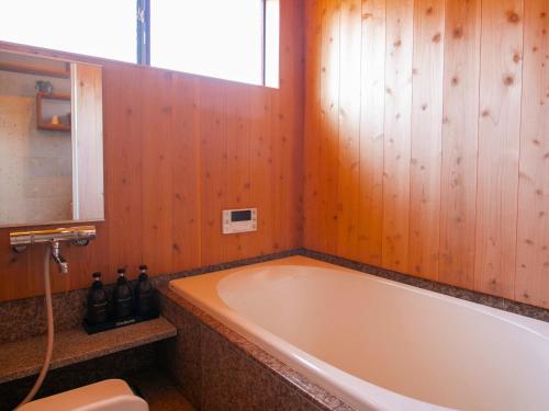 a bath tub in a bathroom with wooden walls at ゆったりとした時間を過ごせる一棟貸切の別荘　たけしま in Naruto