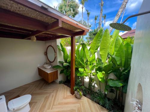 a bathroom with a toilet and green plants at Loku Kedungu - Boutique Resort in Tanah Lot