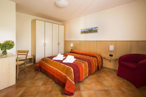 una camera d'albergo con letto e sedia di Residence Corte Camaldoli a Garda
