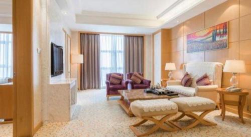 a living room with a couch and a tv at Jinjiang Grandlink Hotel in Quanzhou