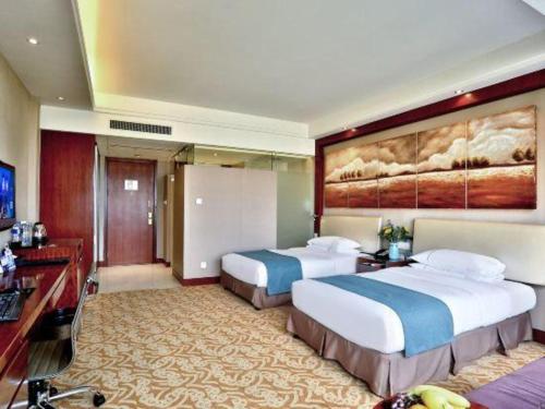 a hotel room with two beds and a television at Jinhua World Trade Hotel in Jinhua