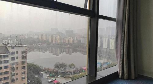 a window with a view of a city and a lake at Yongzhou Chuang Fa Cheng XiaoXiangYi Hotel in Guzhuting