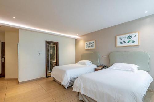 two beds in a hotel room with white sheets at Leisurely Hotel Shenzhen in Shenzhen