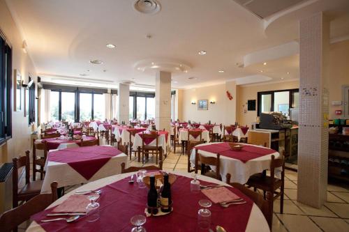 um restaurante com mesas e cadeiras vermelhas e brancas em Hotel Caravel em Sottomarina