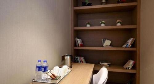a room with a table and shelves with water bottles at East Queen Hotel (Xi'an Beimen Metro Station) in Xi'an