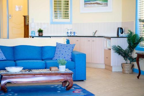 a living room with a blue couch and a table at Beachfront Bliss for Two l Nova Escapes in The Entrance
