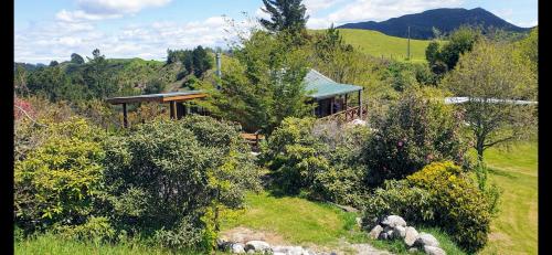 a house in the middle of a field with trees at Rough Meadows - MTB Haven & Good Vibes Retreat in Rotorua